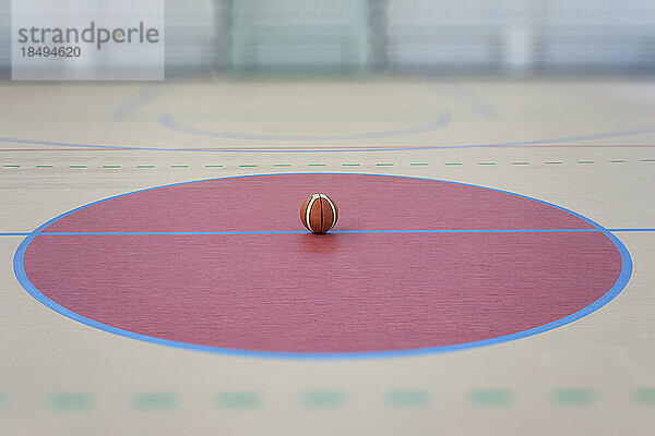 Eine Schulsporthalle mit einem markierten Hallenfußballfeld  einem blau-gelb gestreiften Ball in einem rosa Kreis.