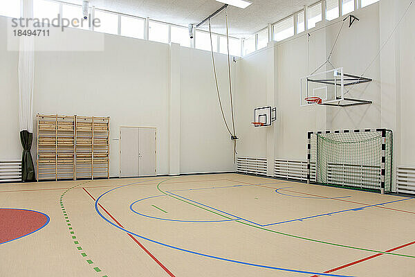Indoor-Basketballplatz in einer Schule. Holzboden und markiertes Feld  ein Korb und ein Rückbrett.
