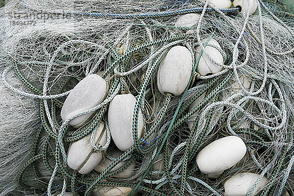 Ein Stapel kommerzieller Fischernetze mit Seilen und Plastikschwimmern.