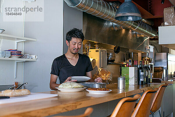 Ein Koch  der in einem Restaurant arbeitet und am Pass Teller mit Essen für den Service vorbereitet