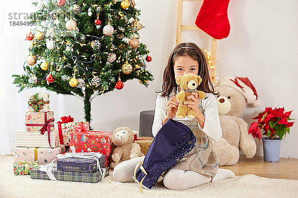 Lächelndes junges Mädchen  das Weihnachtsgeschenke öffnet