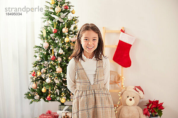 Lächelndes junges Mädchen mit Weihnachtsbaum