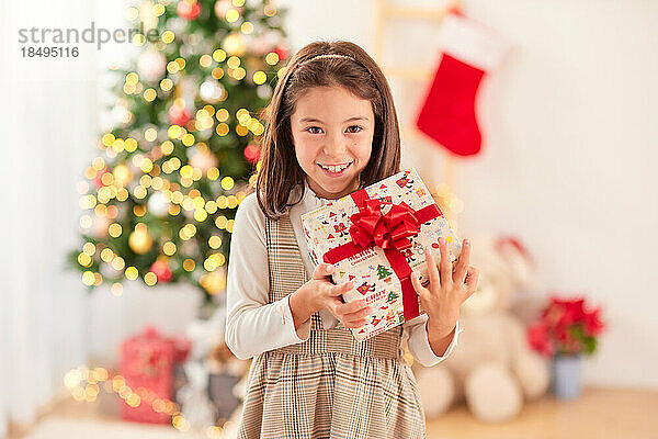 Lächelndes junges Mädchen mit Weihnachtsgeschenk
