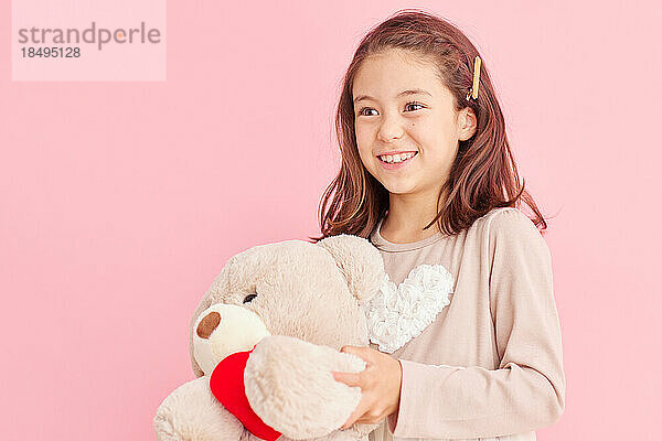 Smiling young girl holding teddy bear