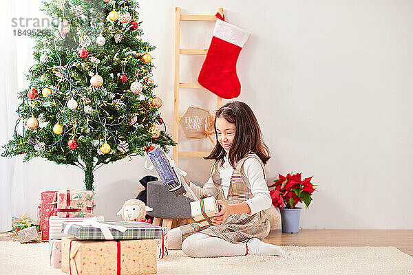 Lächelndes junges Mädchen  das Weihnachtsgeschenke öffnet