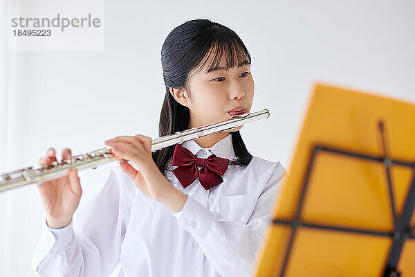 Japanischer Gymnasiast trägt Uniform und übt Musik