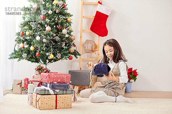 Lächelndes junges Mädchen  das Weihnachtsgeschenke öffnet