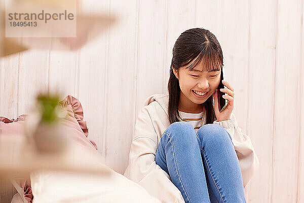 Japanisches Mädchen mit Smartphone im Bett