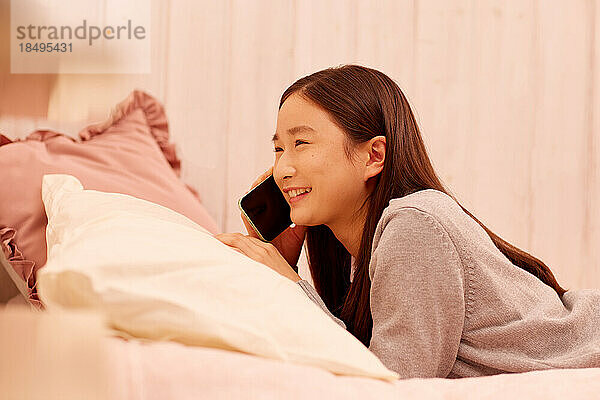 Japanisches Mädchen mit Smartphone im Bett