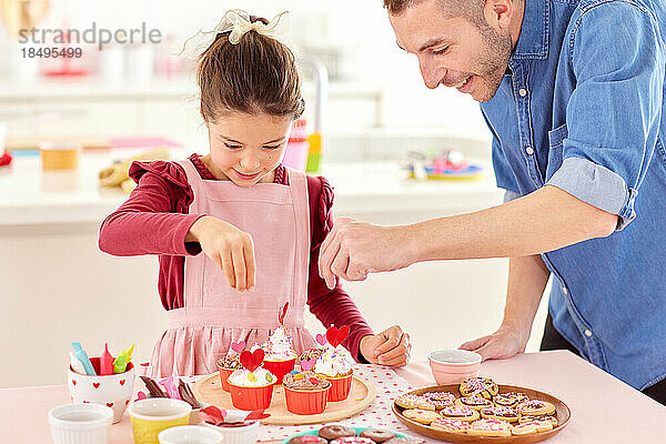 Lächelndes junges Mädchen  das mit seinem Vater Süßigkeiten zubereitet