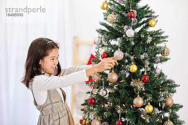Smiling young girl decorating Christmas tree