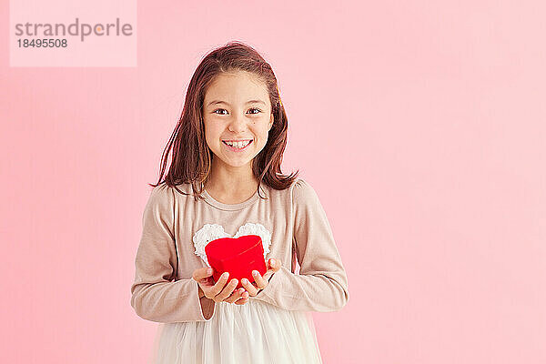 Smiling young girl holding heart