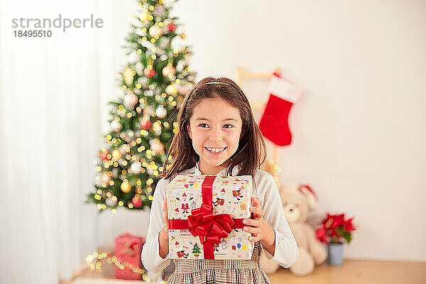 Lächelndes junges Mädchen mit Weihnachtsgeschenk