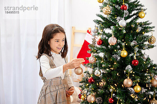 Smiling young girl decorating Christmas tree