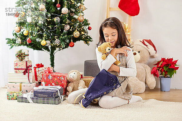 Lächelndes junges Mädchen  das Weihnachtsgeschenke öffnet