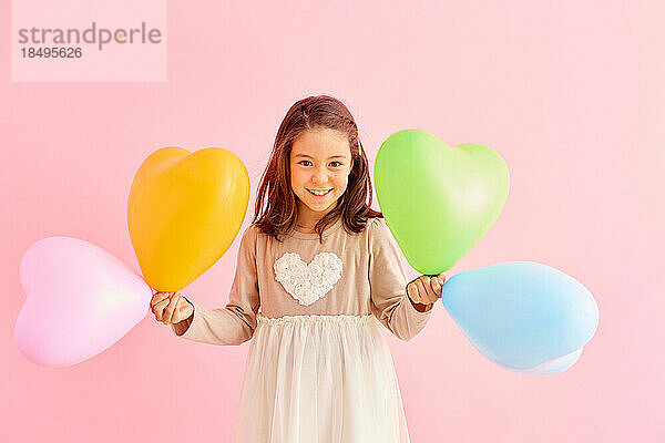 Lächelndes junges Mädchen mit Herzballons