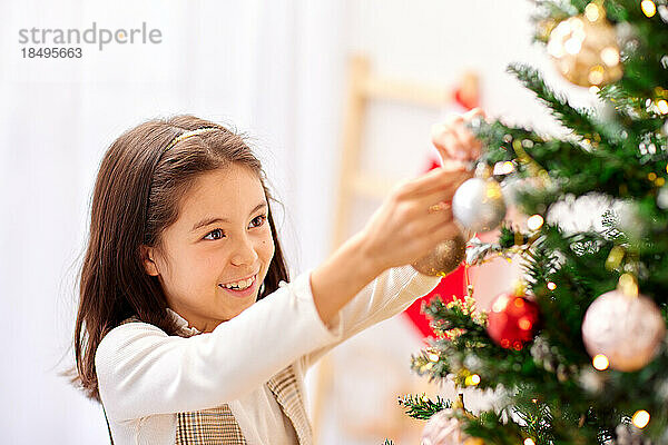 Lächelndes junges Mädchen  das Weihnachtsbaum schmückt