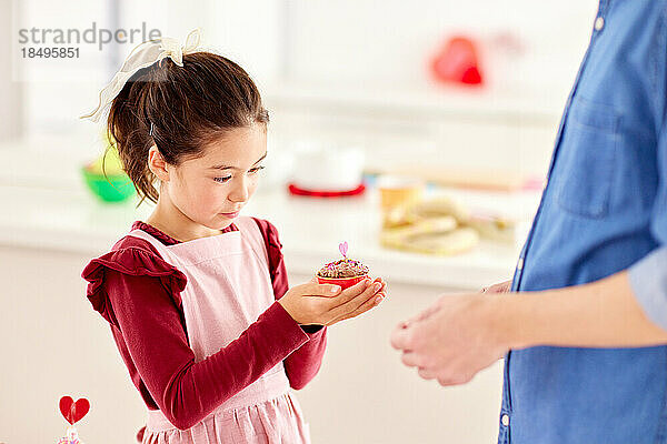 Lächelndes junges Mädchen  das mit seinem Vater Süßigkeiten zubereitet