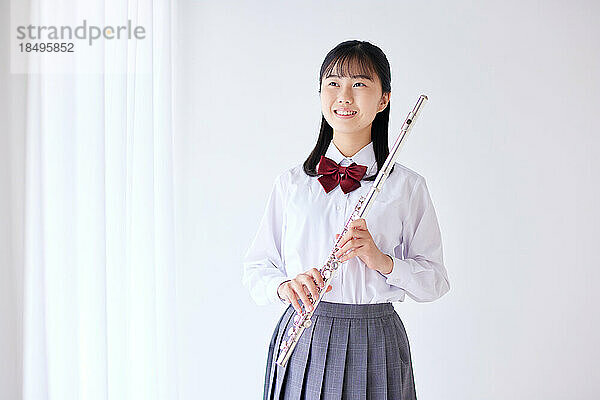 Japanischer Gymnasiast trägt Uniform und übt Musik