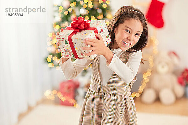 Lächelndes junges Mädchen mit Weihnachtsgeschenk
