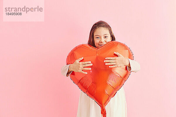 Smiling young girl holding heart