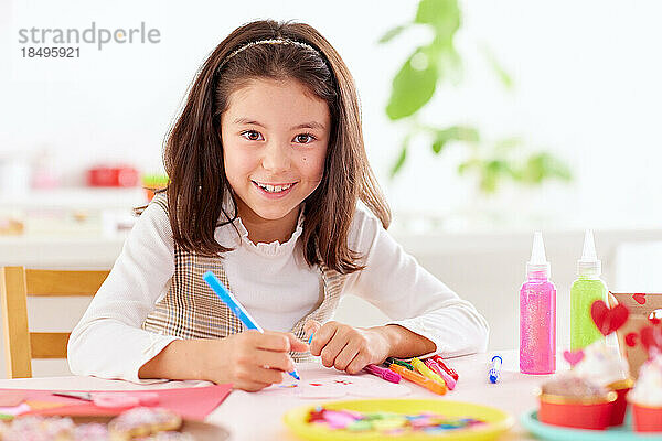 Lächelndes junges Mädchen  das mit Bastelpapier spielt