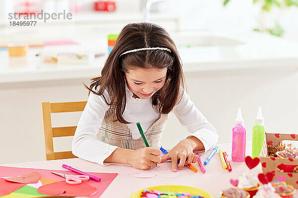 Lächelndes junges Mädchen  das mit Bastelpapier spielt