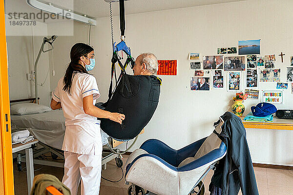 Pfleger bereitet die Schlafenszeit eines behinderten Patienten in seinem Zimmer im Altersheim vor.