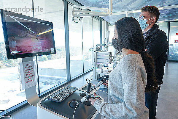 Interne Studierende der Verdauungschirurgie trainieren an einem Lap-Sim-Simulationsgerät für chirurgische Eingriffe. Die Schüler sollen mit chirurgischen Instrumenten einen Knoten knüpfen.