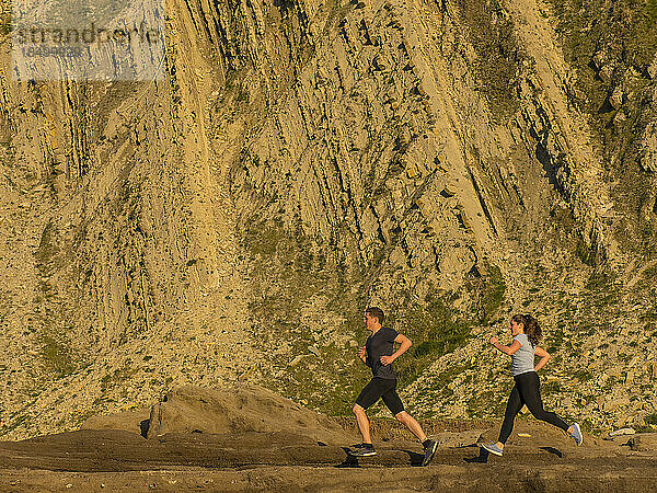 Mann und Frau laufen auf einem Singletrail auf der Klippe von Getxo