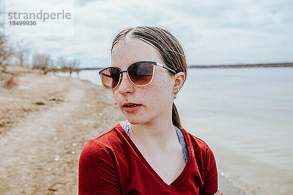 Teenager-Mädchen steht an einem sonnigen Tag neben dem See