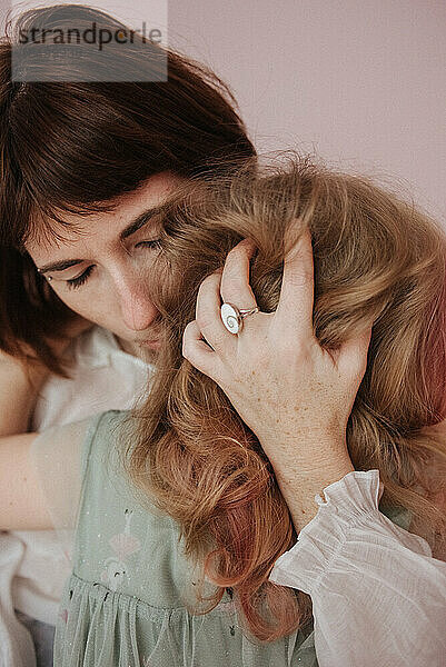 Mutter umarmt ihre Tochter und streichelt ihr Haar