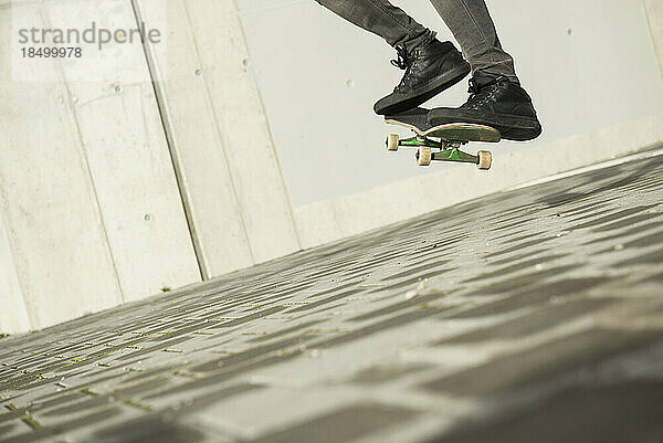 Untere Schnittansicht eines Mannes  der mit einem Skateboard in der Luft springt  München  Bayern  Deutschland