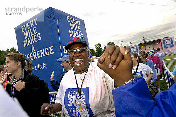 Eine afroamerikanische Frau bekommt zu Beginn eines Brustkrebs-Spaziergangs in Detroit einen Händedruck.