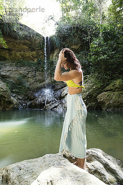 Solo-Frau im Bikini mit Handtuch an einem Wasserfall in Puerto Rico