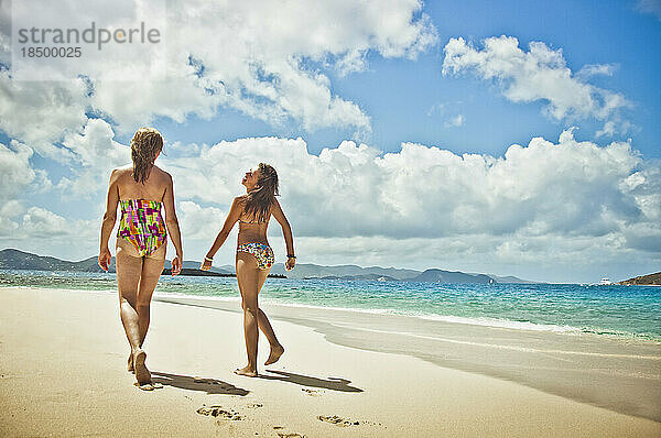 Teenager-Mädchen und Mutter spazieren am Strand.