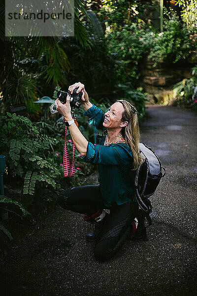 Glückliche Frau fotografiert mit Kamera im tropischen Wald