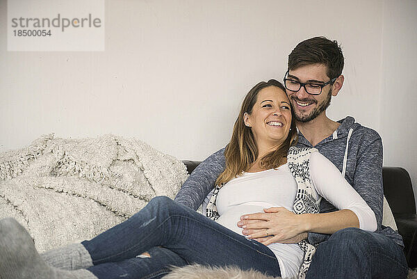 Schwangere Frau mit ihrem Mann auf dem Sofa  München  Deutschland