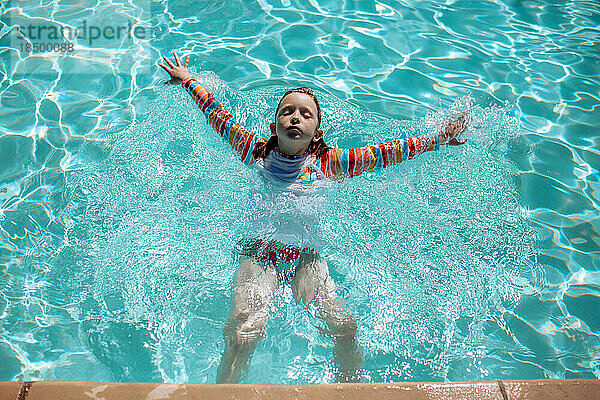 Junges Mädchen schwimmt an einem sonnigen Tag auf dem Rücken im Pool