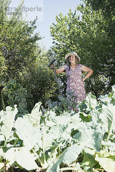 Glückliche Frau mit einem Rechen im Garten  Altötting  Bayern  Deutschland
