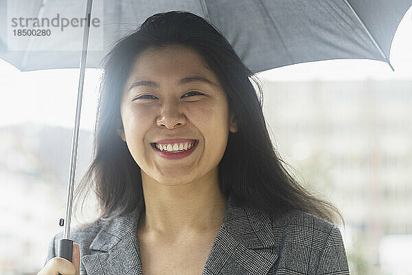 Porträt einer glücklichen jungen Frau unter einem Regenschirm  Freiburg im Breisgau  Baden-Württemberg  Deutschland