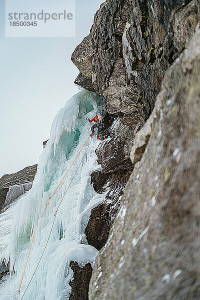 Mann klettert beim Skibergsteigen auf steiles Eis und Felsen