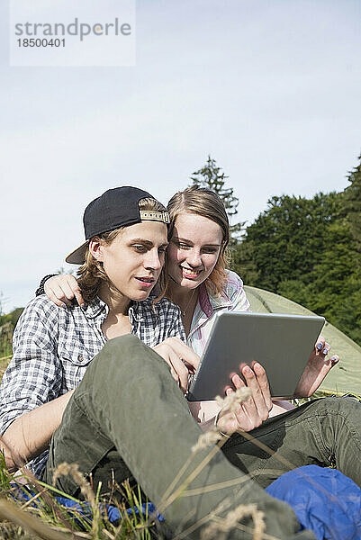 Junges Paar nutzt digitales Tablet vor Zeltlager  Bayern  Deutschland