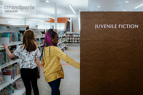 Zwei Mädchen im Grundschulalter erkunden die öffentliche Bibliothek