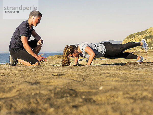Mann und Frau machen Liegestütze am Strand von Azkorri