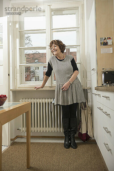 Ältere Frau steht in der Küche und lächelt  München  Bayern  Deutschland