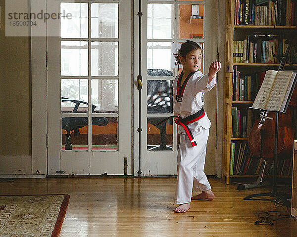 Ein junges Mädchen in Uniform übt zu Hause Taekwondo