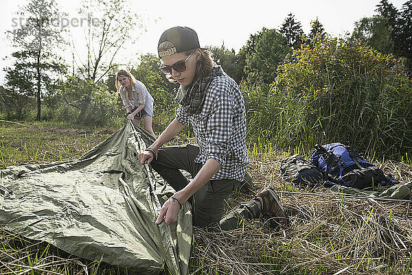 Junges Paar baut Zelt in einem Wald auf  Bayern  Deutschland