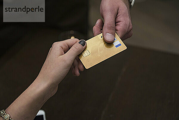 Ausgeschnittenes Bild von Händen  die im Restaurant eine Kreditkarte halten