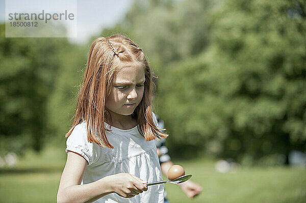 Mädchen balanciert ein Ei auf einem Löffel im Park  München  Bayern  Deutschland